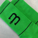 Bright green athletic socks with a black stylized 'm' logo and thin black horizontal stripes.