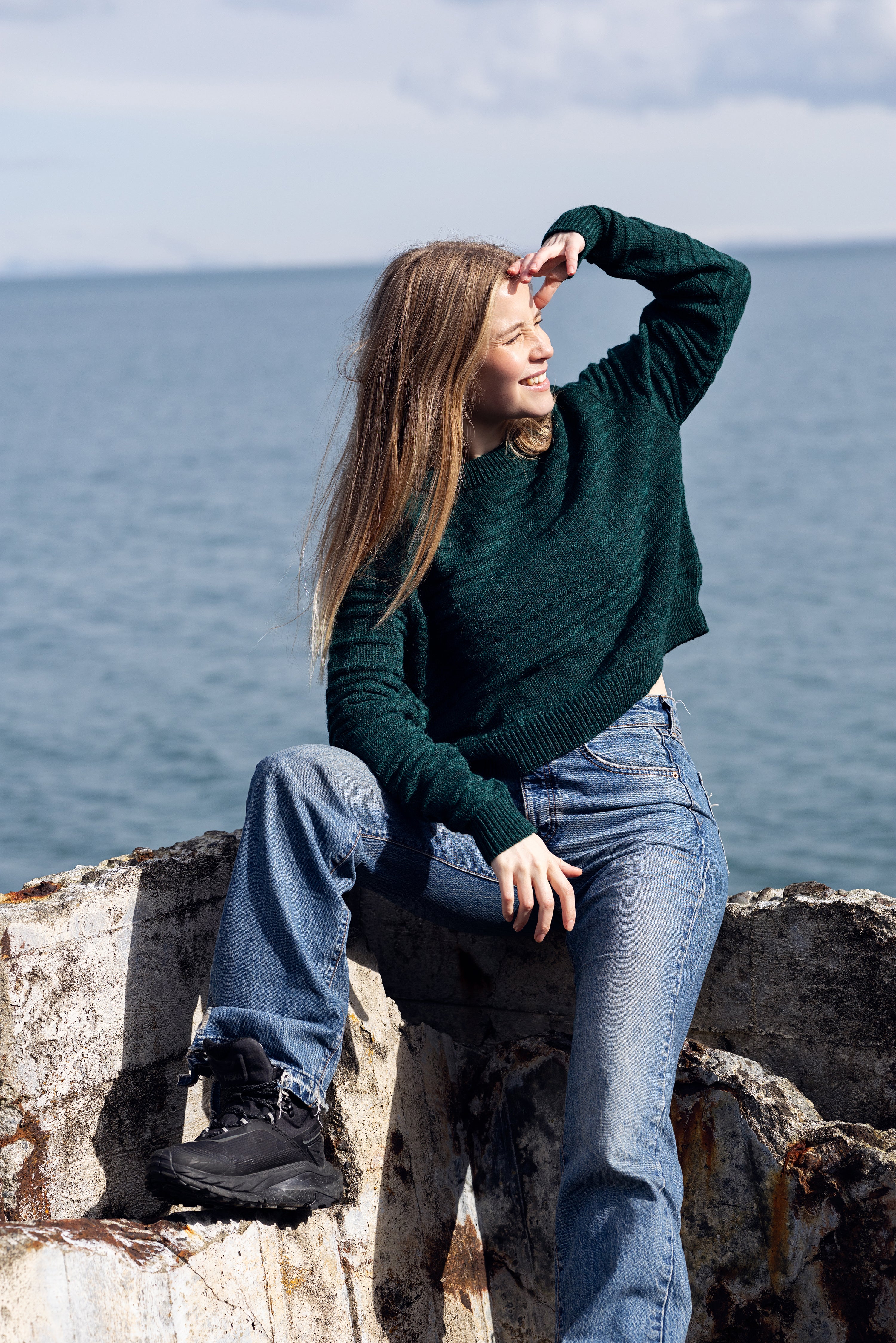 Cropped wool sweater in deep aqua green in front of ocean