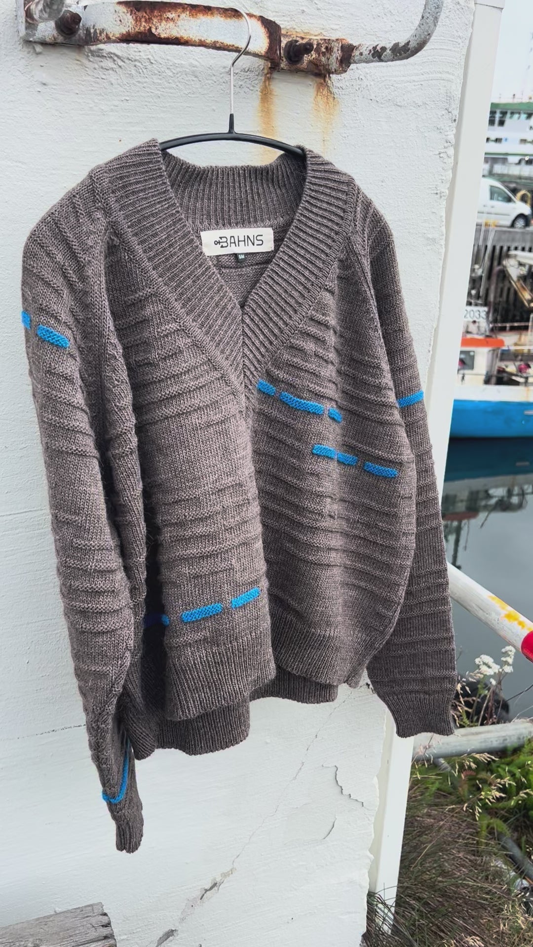Brown wool sweater with blue knit details swaying in the wind